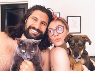 Kayvan Novak posing with his spouse, and pets