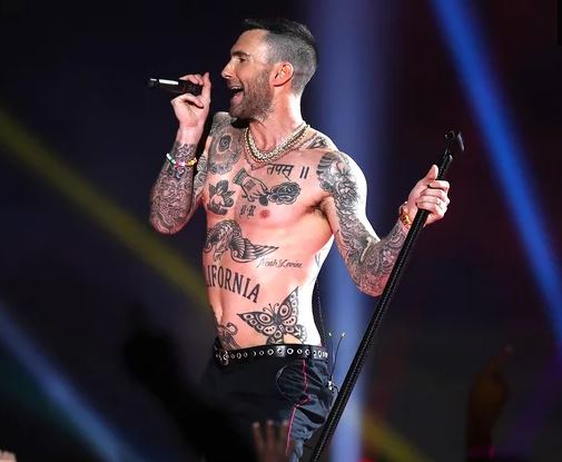 Adam Levine performing shirtless, revealing his tattoos